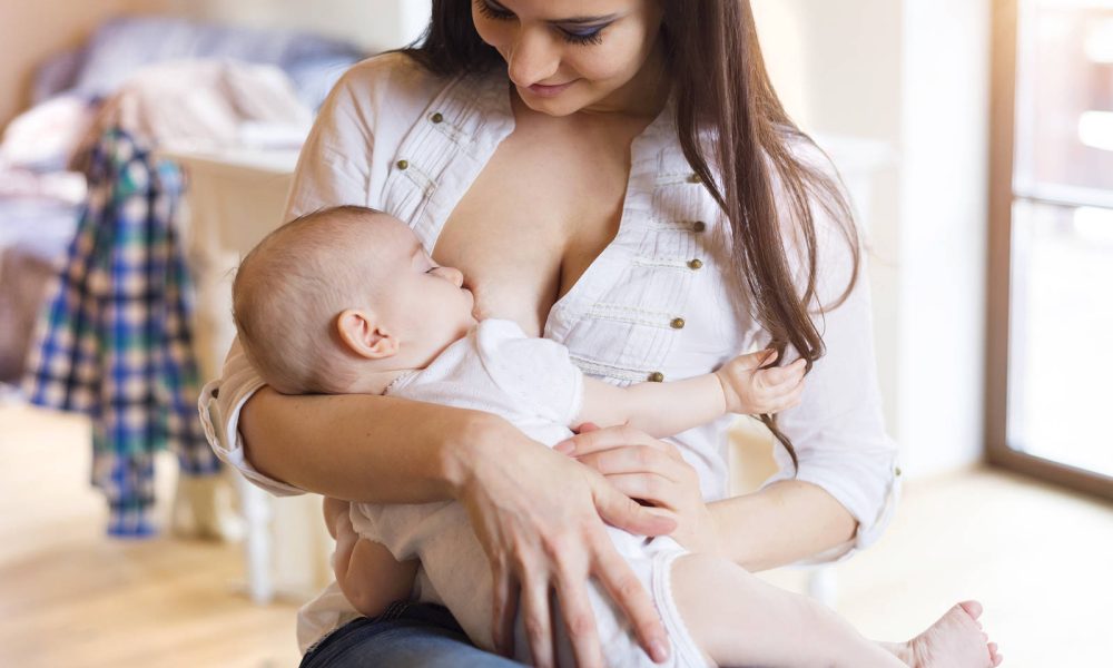 Mother breastfeeding her little baby girl in her arms.